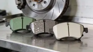 Three automotive brake pads with brake rotor background