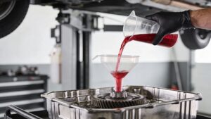 Pouring transmission fluid into car gearbox with funnel