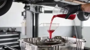 Pouring transmission fluid into car gearbox with funnel