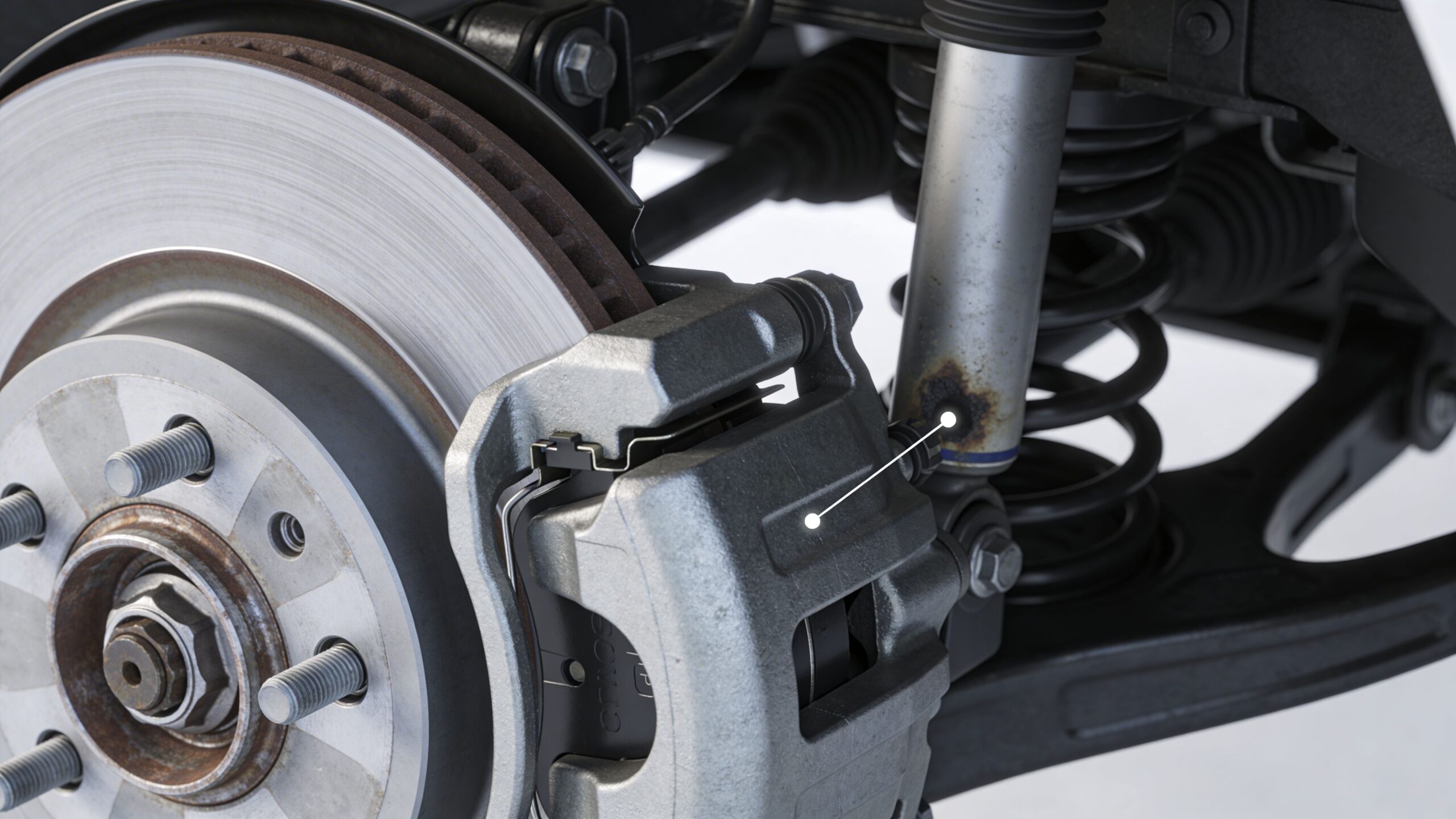 Close-up view of a car suspension system with a brake caliper and a rusted shock absorber component.