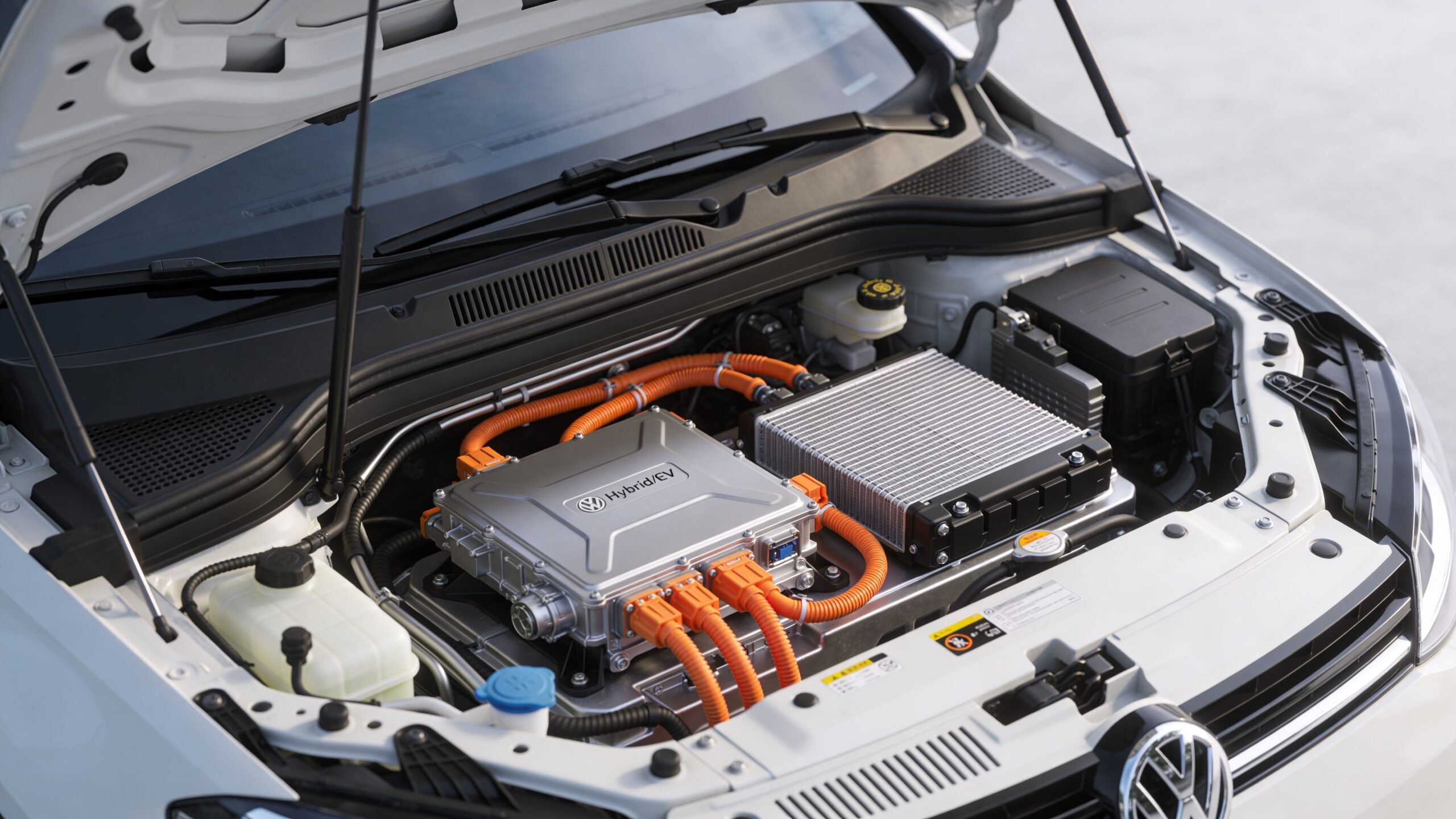 Open hood of a modern Volkswagen hybrid vehicle engine bay showing electrical components and power cables.
