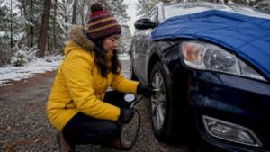 Woman checking tire pressure on car outdoors
