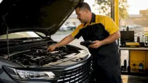 Mechanic inspecting open car engine in garage
