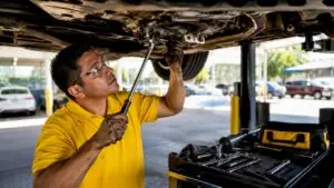 Mechanic inspecting DSG transmission under SUV