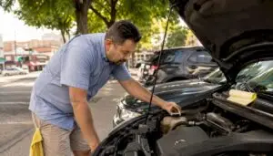 Man inspecting car engine coolant level outdoors