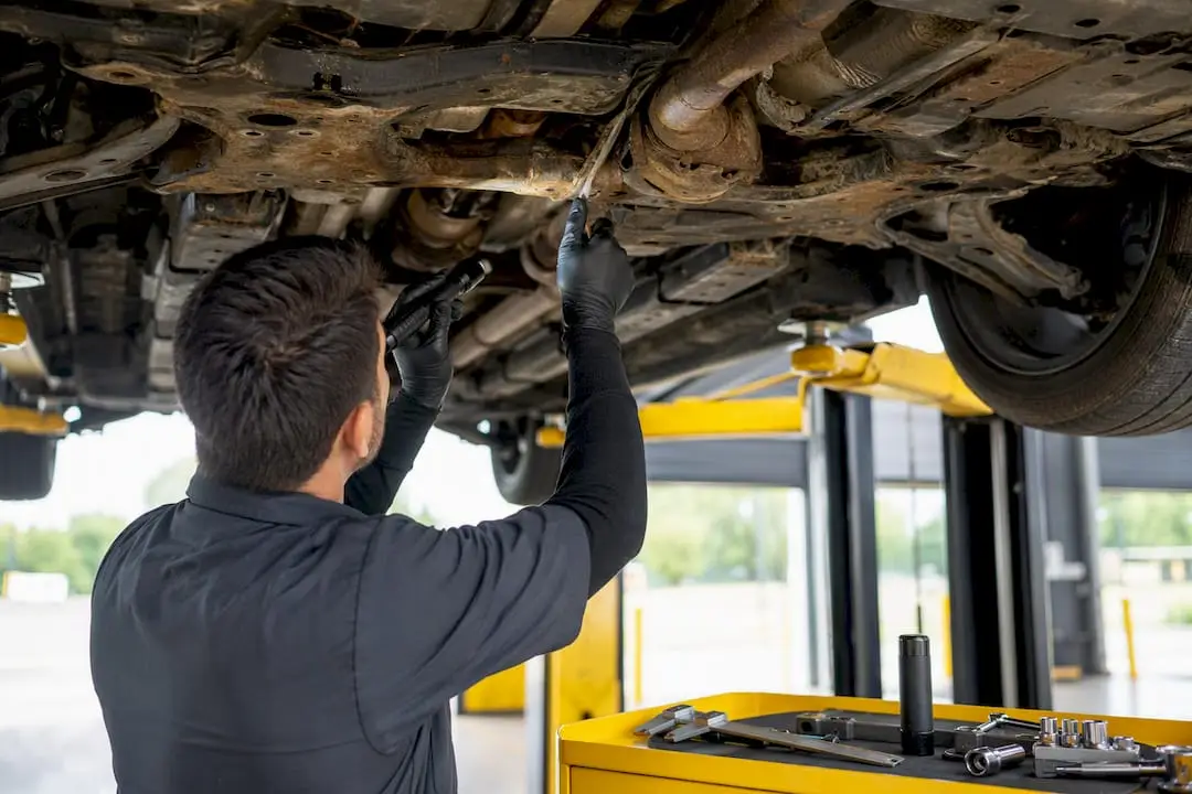 Technician inspecting car undercarriage on lift