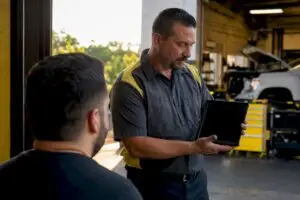 Technician showing ASE certification on tablet