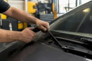 Hands replacing windshield wiper blade on windshield