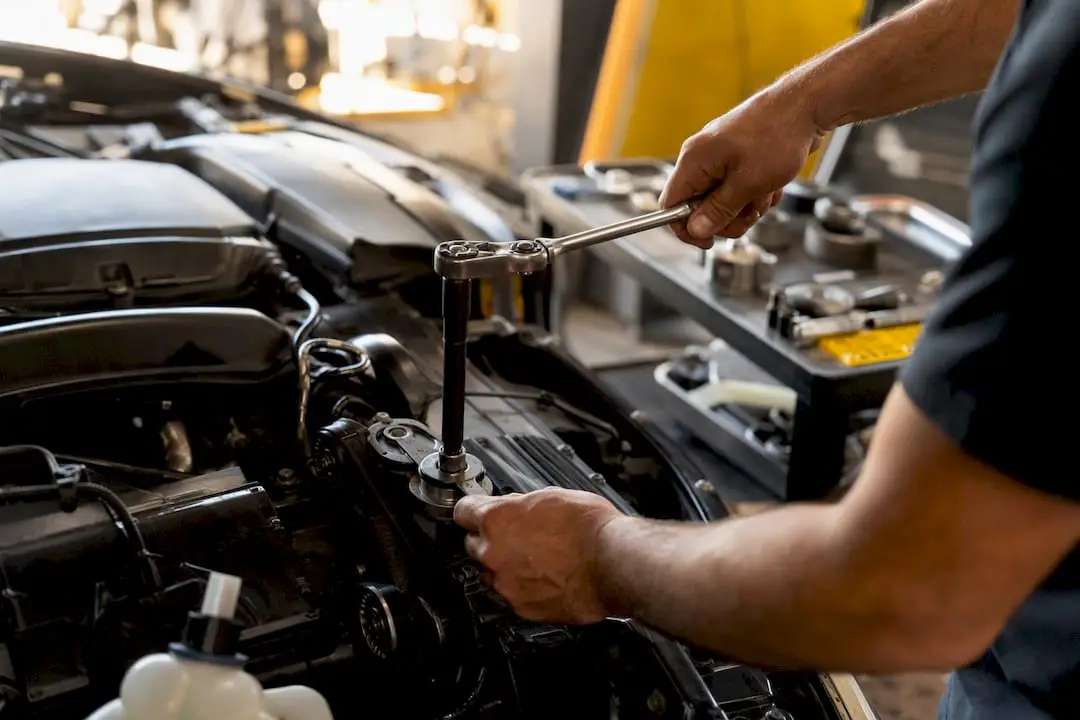 Hands using serpentine belt tensioner tool