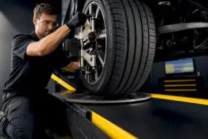 Technician adjusting wheel on alignment rack