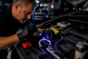 Technician inspecting vehicle AC lines for leaks
