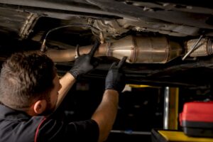 Technician inspecting exhaust sensors and converter