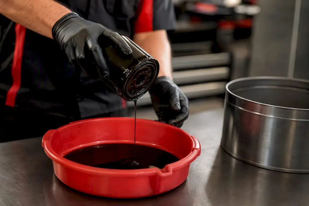 Technician draining used oil filter for recycling