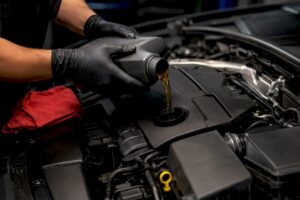 Technician adding oil to engine