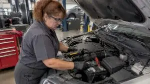 Technician testing a car battery in a repair bay